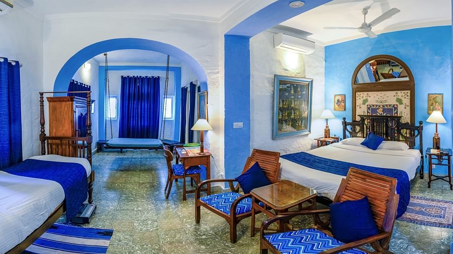 Hill Fort Kesroli 14th Century Alwar - interior view of the Hindola Mahal - Countryside View with white and blue decor, ceiling fan and a queen size bed 