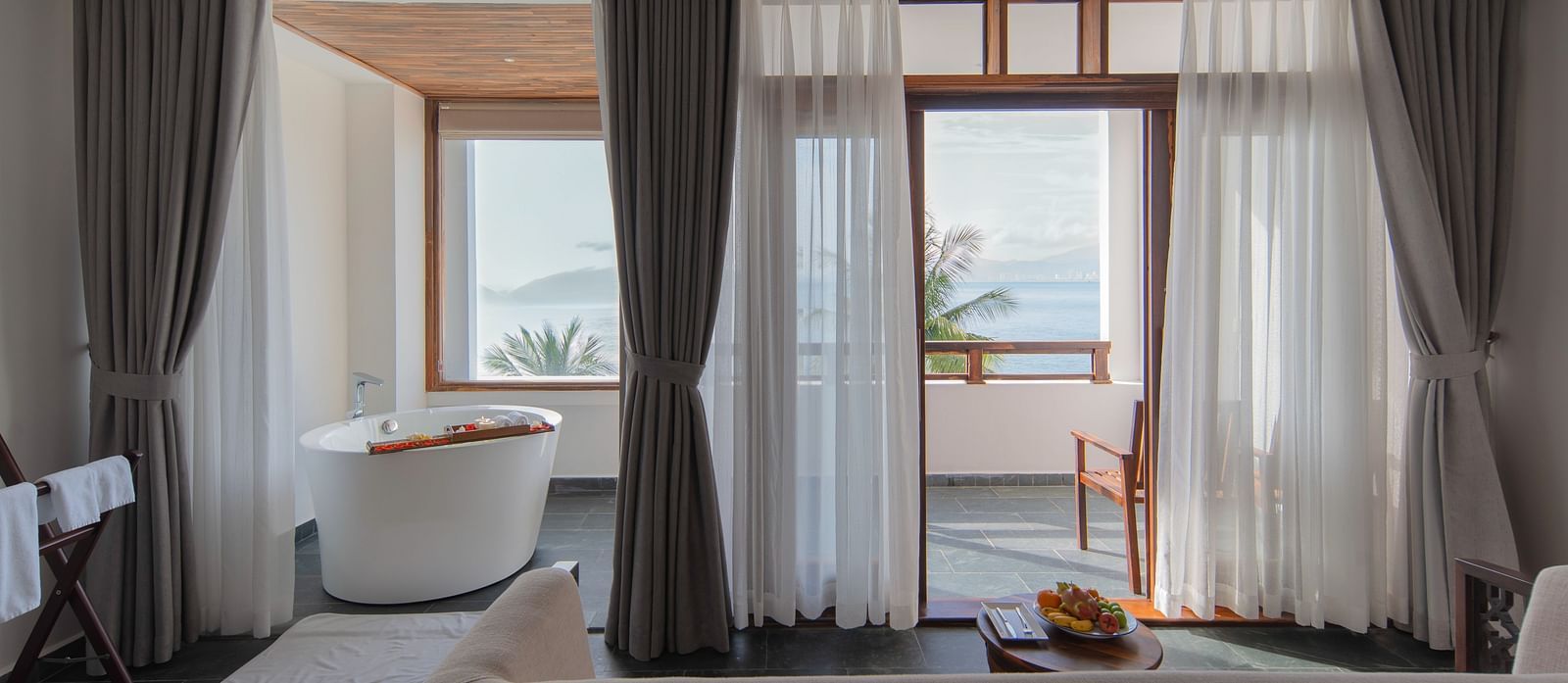 A view of a bathtub and wooden chairs placed in a balcony in one of our rooms - Alibu Resort Nha Trang