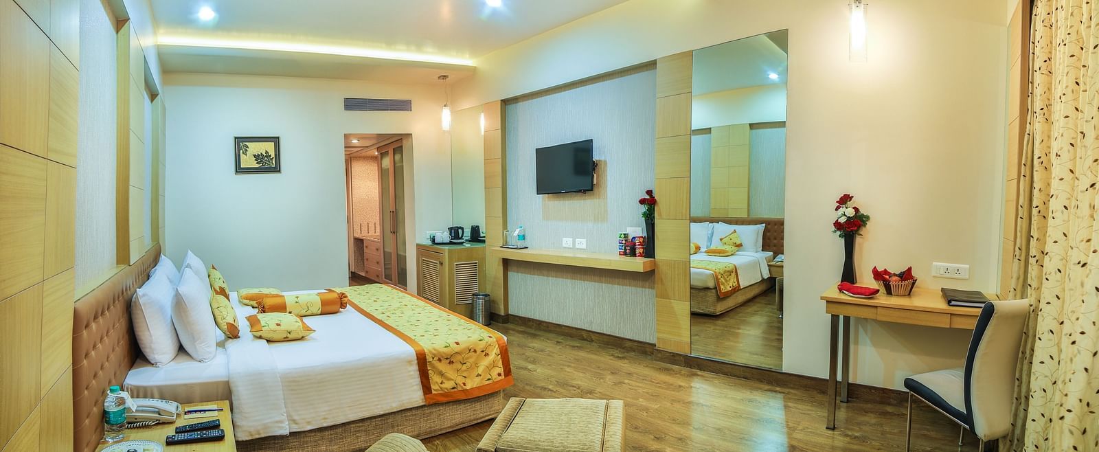A king-sized hotel room with a contemporary design, a comfortable seating area, and a large television A grand hotel suite with an opulent red and white decor, large bed, and seating area, reflecting a traditional style at Sitara Luxury Hotel in Hyderabad 