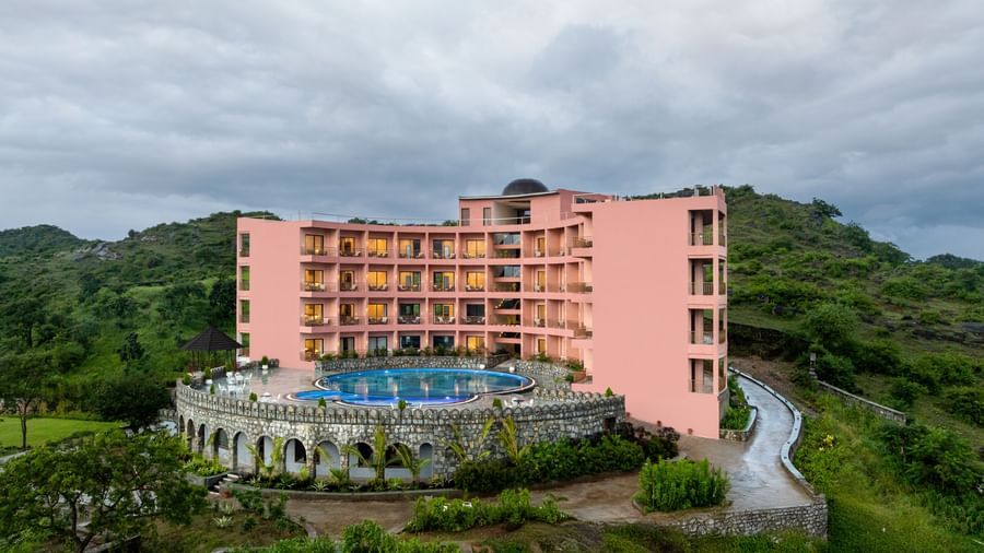 Facade of the Osian Valley Resort & Spa, a multi-story, pink-coloured structure with a large swimming pool in the foreground.