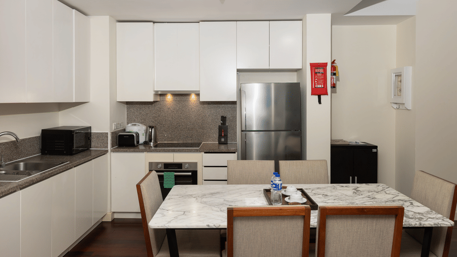 Fully equipped kitchen in the Three Bedroom Family Suite at Central Mansions, Phnom Penh with modern appliances, dining table, and ample storage.