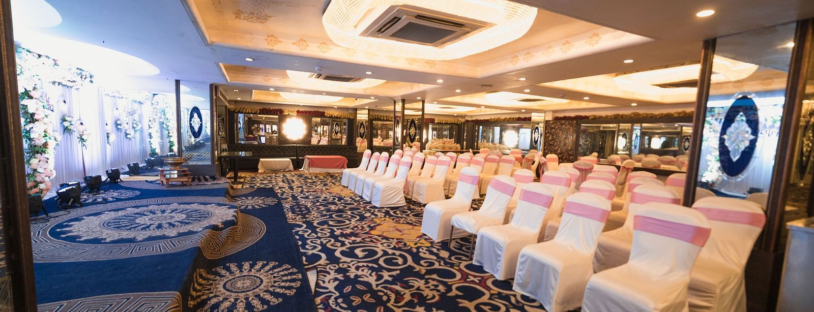 Magadh showcasing blue patterned flooring, neatly arranged tables and chairs, and contemporary lighting.