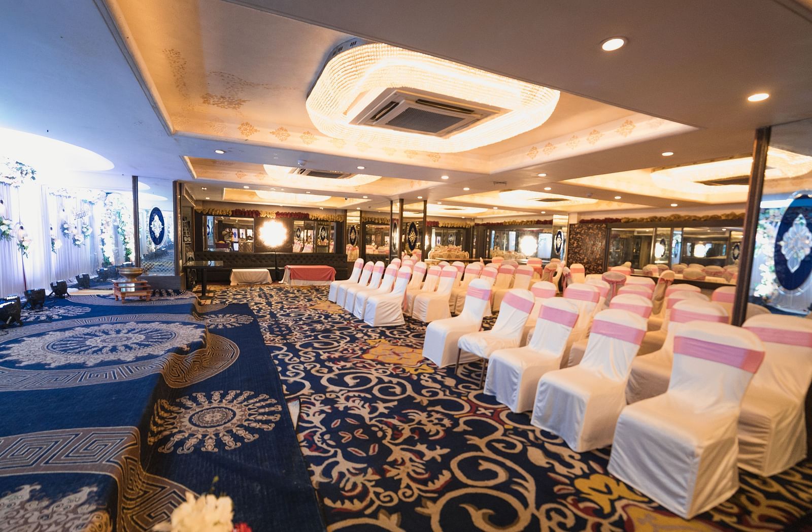 Magadh showcasing blue patterned flooring, neatly arranged tables and chairs, and contemporary lighting.