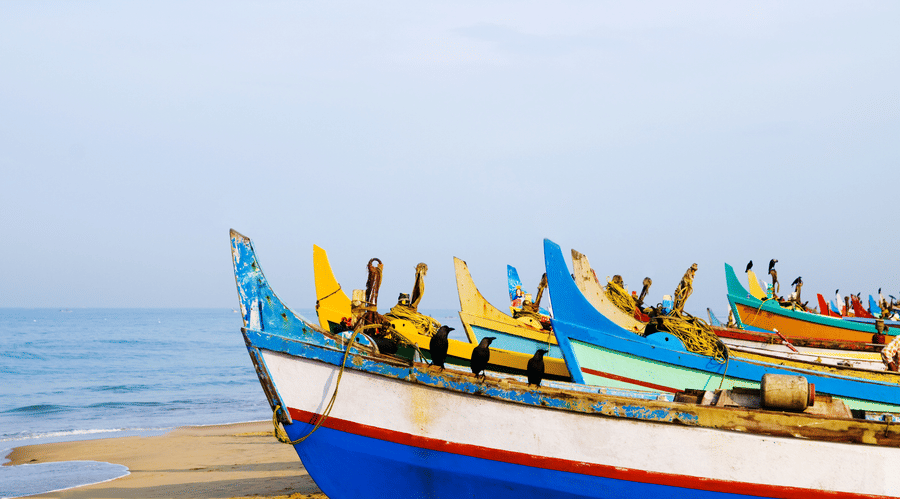 Many boats on the beach with blue sky in the background