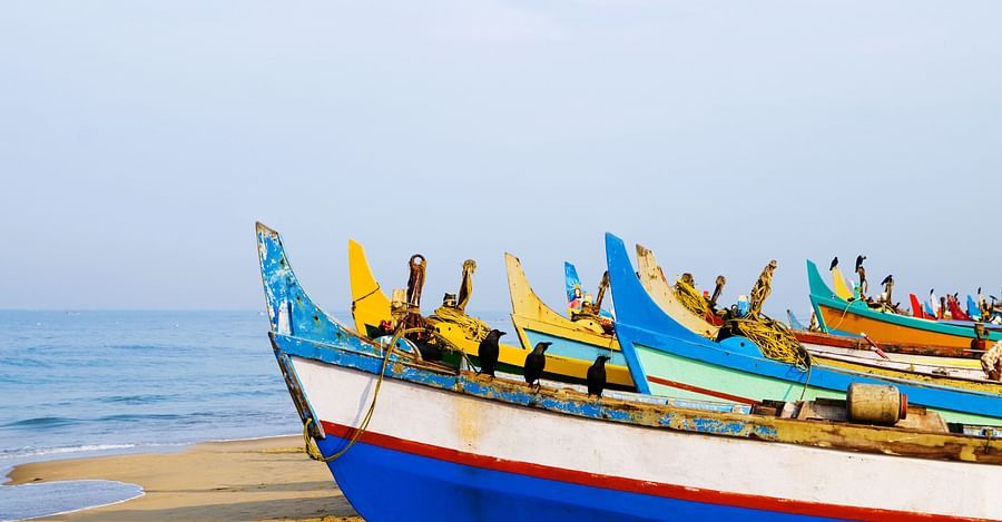 Many boats on the beach with blue sky in the background