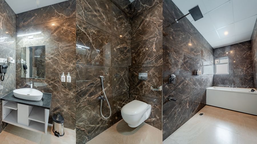 Bathroom in the suite with dark marble-like tiles and a modern bathtub | Studio Suite | Pravasa Hotel, Vijayapura