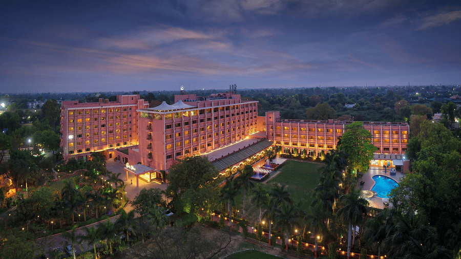 The buildings featuring dense trees, plants and a pool with the evening sky in the backdrop. 