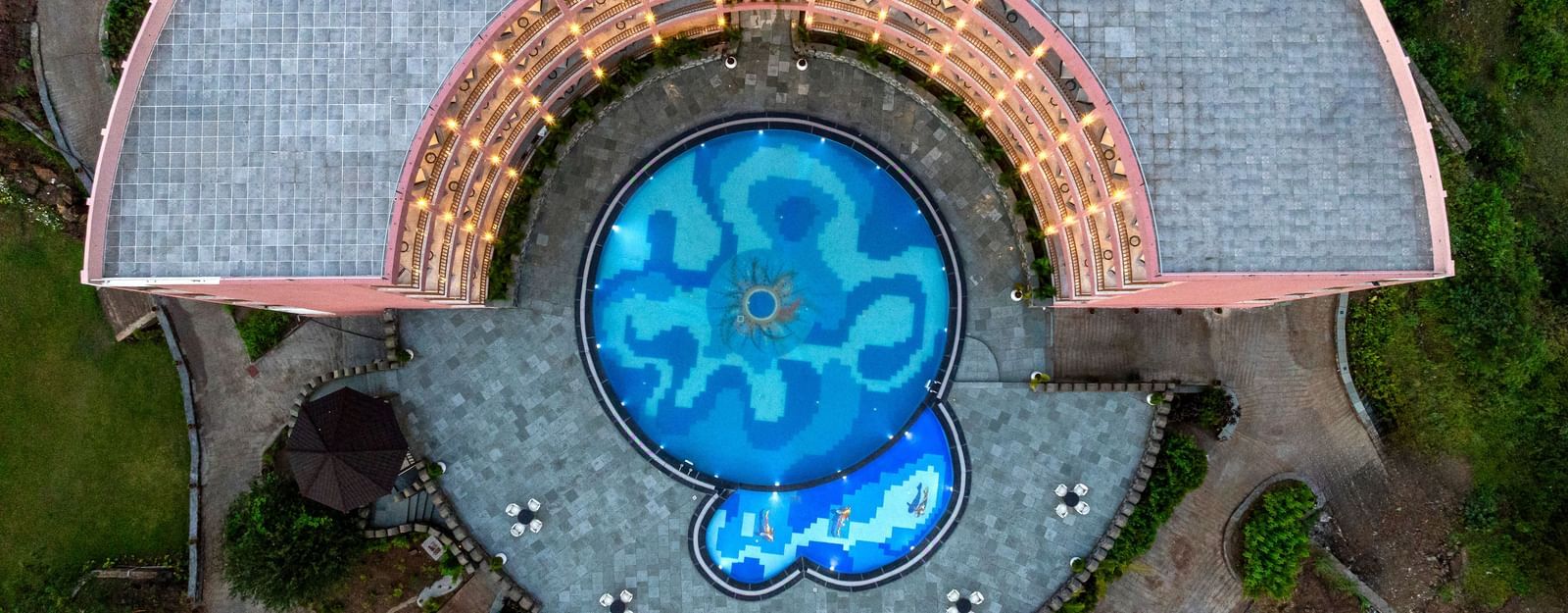 An aerial view of the Osian Valley Resort & Spa showing a central blue-tiled swimming pool partially surrounded by a building.