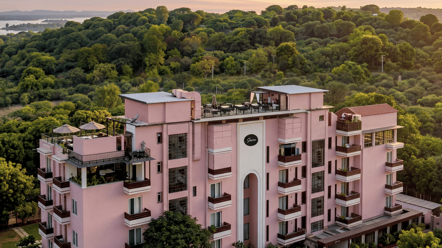 A view of the pink property building facade showing balconies, windows, lush greenery at The Sierra - By The Lake.