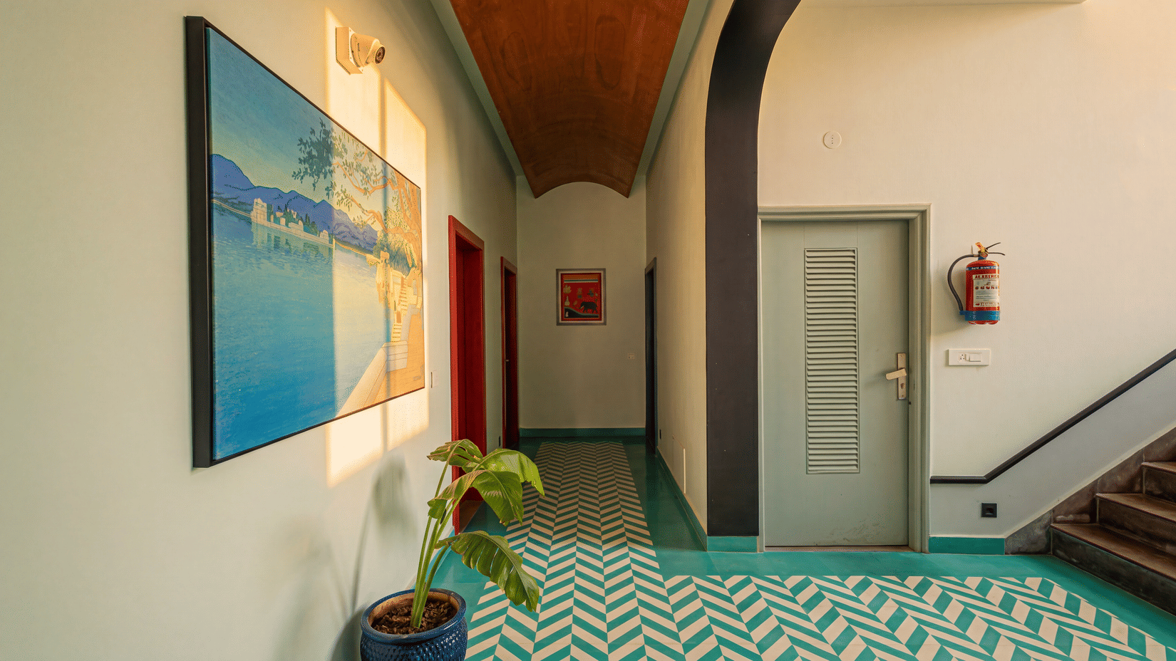 An indoor lobby with a chevron patterned tiled floor, a painting on the wall, a door, a staircase at The Sierra - By The Lake.