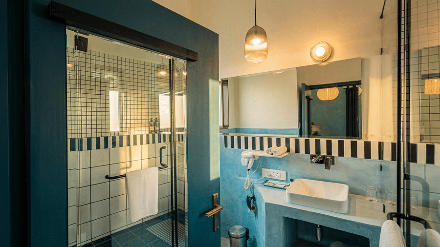A sleek bathroom showing a glass cubicle, washbasin vanity counter, hanging lights, and wall mirror at The Sierra - By The Lake.