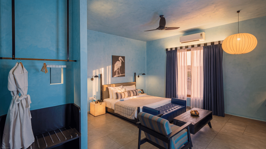 A modern bedroom with a king size bed, seating area, ceiling fan, large hanging lamp, and wardrobe at The Sierra - By The Lake.