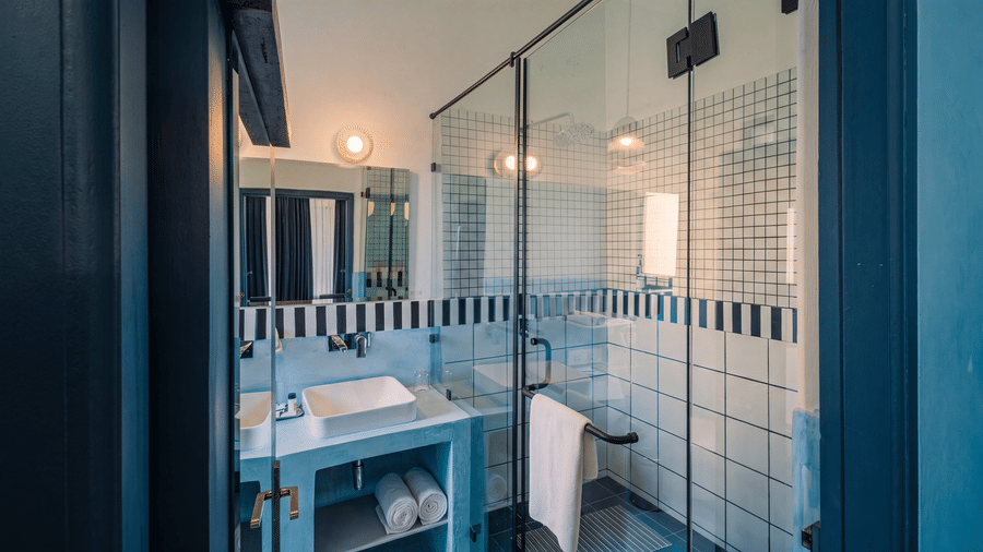 A contemporary bathroom equipped with a glass shower enclosure, washbasin unit, large mirror, and towels at The Sierra - By The Lake.