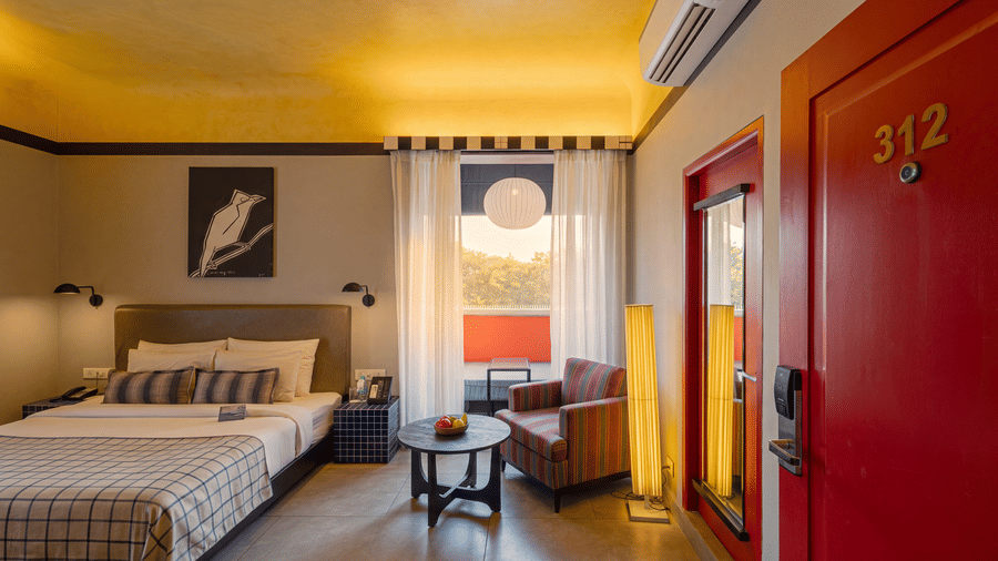 A bedroom at The Sierra - By The Lake featuring a king size bed, a small seating corner with an armchair, and an entrance door numbered 312.