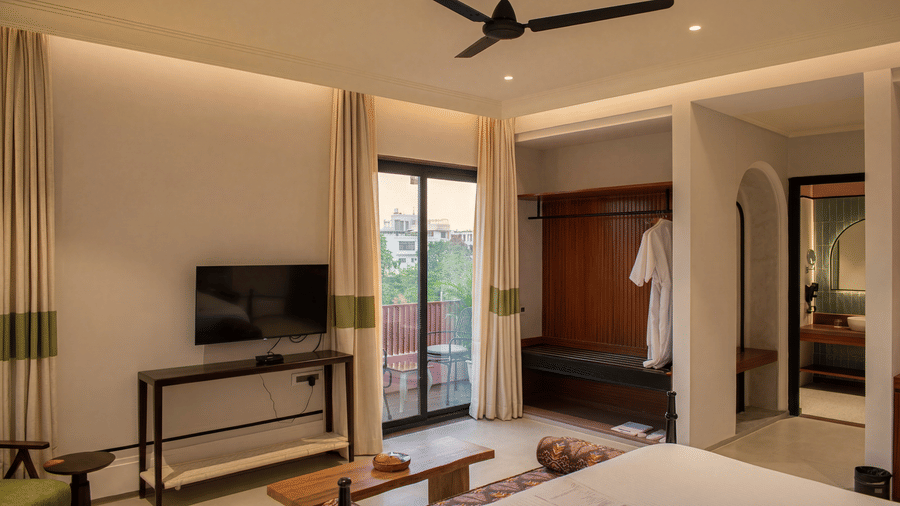 A bedroom interior showing a television on a console table, a sliding glass door, and an open wardrobe at The Sierra - By The Lake.