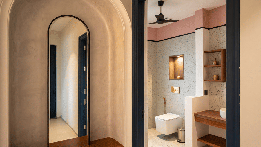 A dual view displaying an arched full-length mirror in a corridor, a wall-mounted toilet, and a sink vanity at The Sierra - By The Lake.