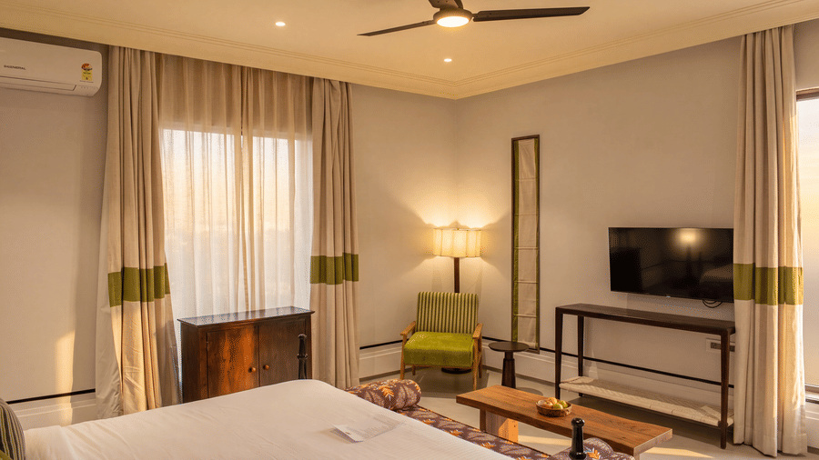 A bedroom featuring a king size bed, a television on a long wooden table, and draped curtains at The Sierra - By The Lake.