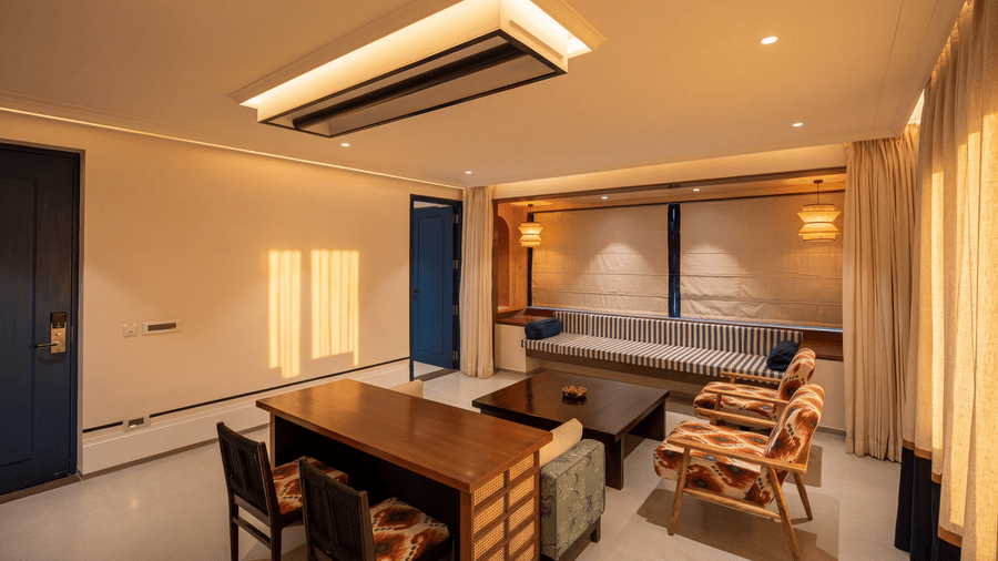 A spacious living space with a wooden desk with chairs, a grey sofa, and a large modern ceiling light at The Sierra - By The Lake.