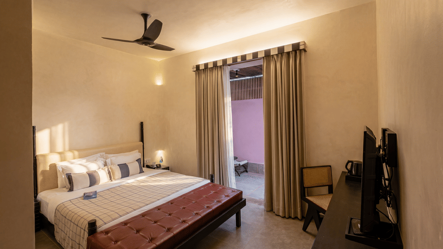 A well lit bedroom featuring a double bed with cushions, wooden benches, a ceiling fan, and long curtains at The Sierra - By The Lake.