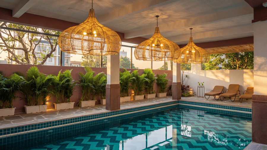 A swimming pool area illuminated by ornate hanging chandeliers next to a wall of hedges at The Sierra - By The Lake.