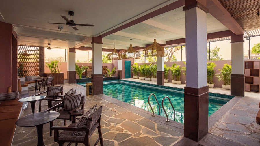 A pool deck featuring a swimming pool, tables, chairs, a ceiling fan under a covered roof at The Sierra - By The Lake.