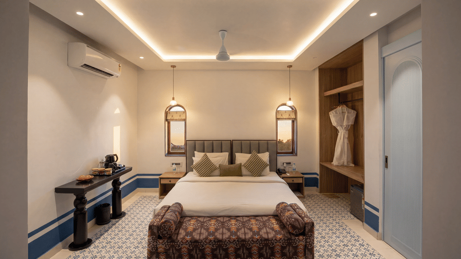 A bedroom at The Sierra - By The Lake featuring a king size bed with cushions, bedside tables with lamps, and a wooden open closet.