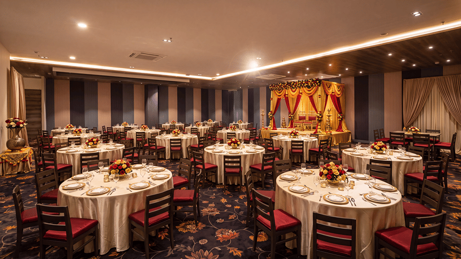 Elegant restaurant dining area with round tables, white table settings, upholstered chairs and warm ambient lighting.