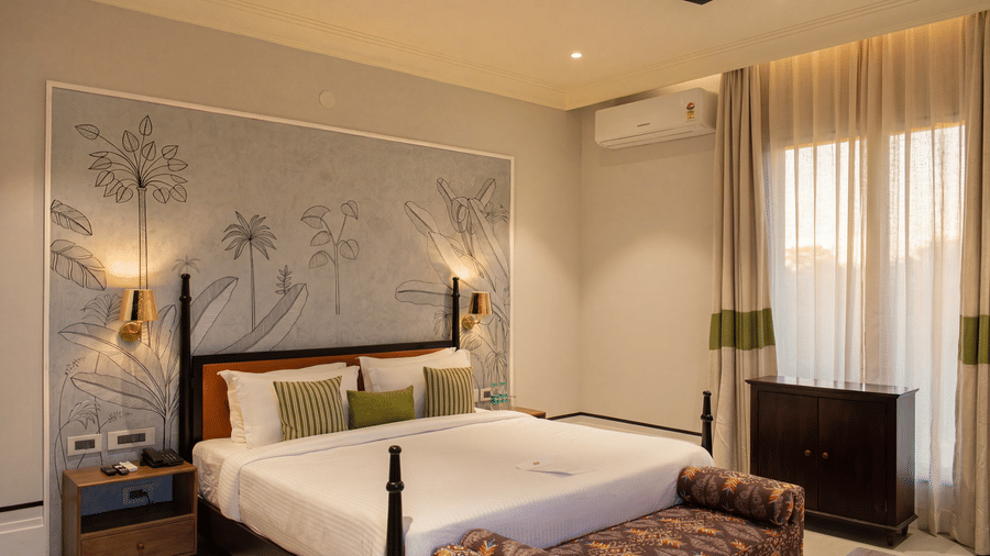 A bedroom area with a king size bed against a patterned wall, a dark wooden cabinet, and long curtains at The Sierra - By The Lake.