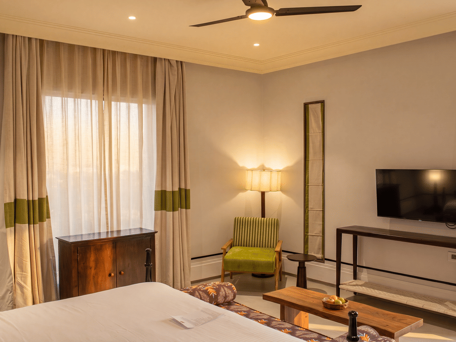 A bedroom featuring a king size bed, a television on a long wooden table, and draped curtains at The Sierra - By The Lake.