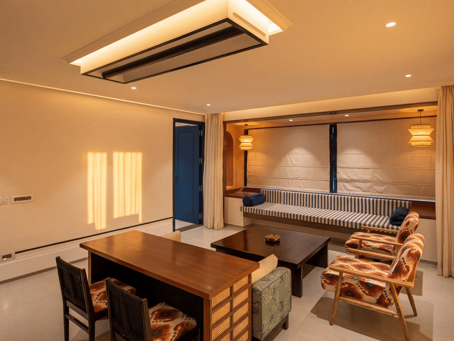A spacious living space with a wooden desk with chairs, a grey sofa, and a large modern ceiling light at The Sierra - By The Lake.