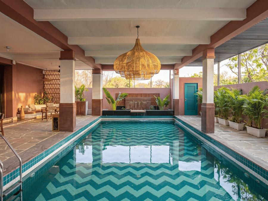 A symmetric view of a covered indoor swimming pool featuring hanging lamps, potted plants at The Sierra - By The Lake.