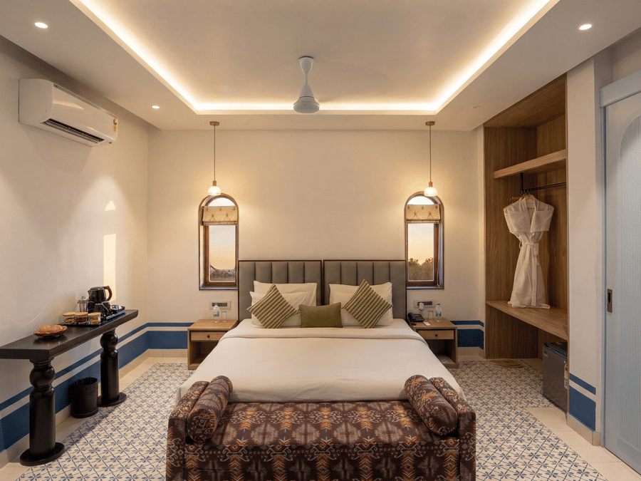 A bedroom at The Sierra - By The Lake featuring a king size bed with cushions, bedside tables with lamps, and a wooden open closet.