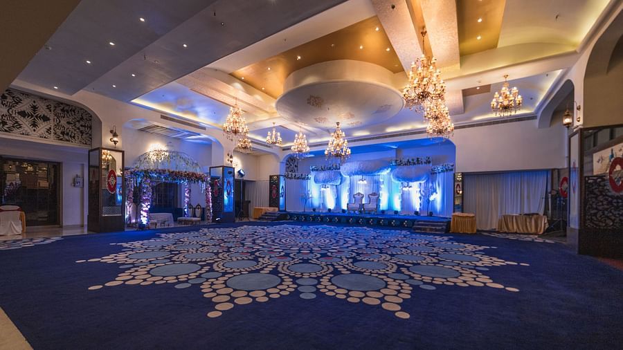 Kohinoor showcased with its large, ornate blue carpet design, spacious layout, and elegant lighting.