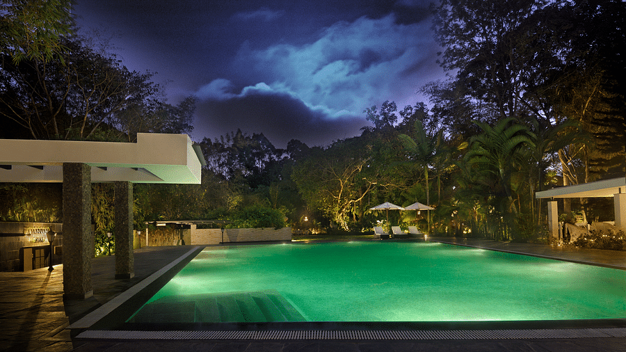 Outdoor swimming pool surrounded by trees during night with with dim light -Amanvana Spa Resort, Coorg - Luxury Resort