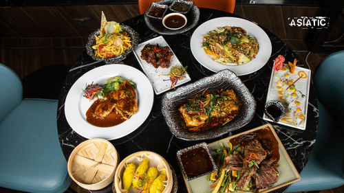 Table with assorted dishes, bowls, bread, and sides arranged for a meal at Asiatic Rooftop Bar and Restaurant.