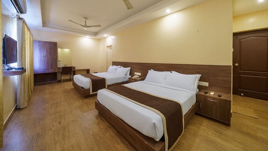 Side view of spacious room with two beds and television at Wyt Hotels, Rameswaram