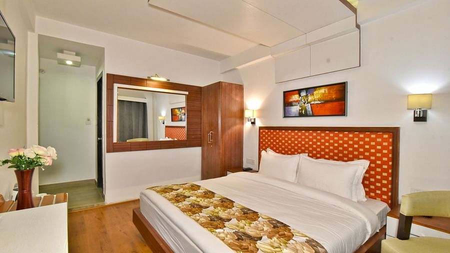 Bedroom with a portrait hanging on the wall above the bed at DLS Hillcrest Resort, Shimla.