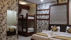 A spacious room at Hotel Uday Palace featuring a large mirror to the side and a neatly made bed.