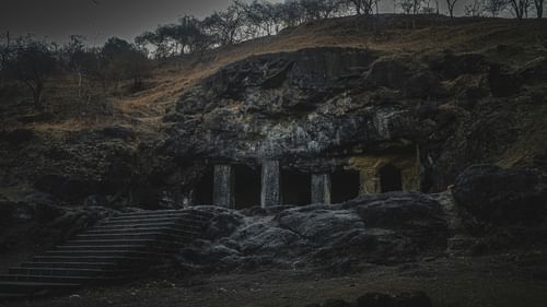 Stone staircase leading to a cave entrance with carved pillars.