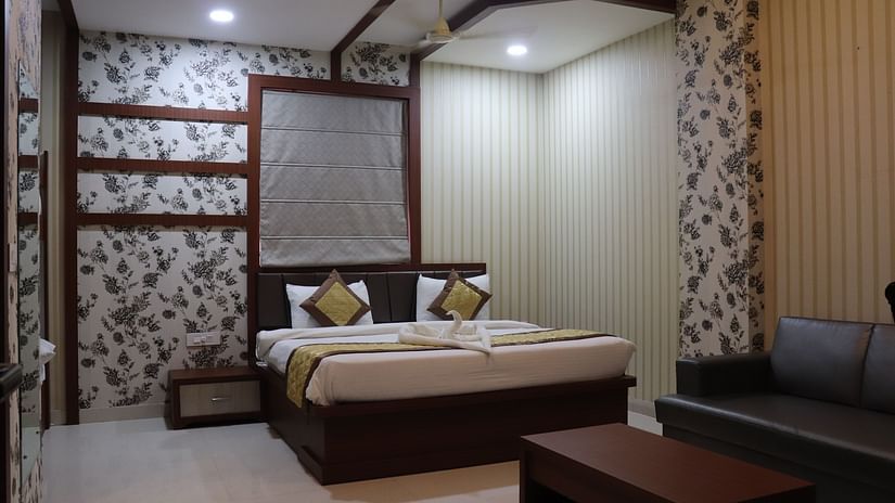 A spacious room at Hotel Uday Palace with a neatly made bed and bright lighting.