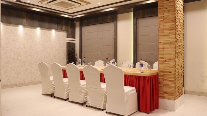 A modern conference-style banquet hall with white chairs and red accents, perfect for events at banquet halls in Varanasi -  Hotel Uday Palace.