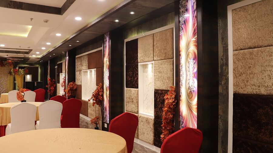 Round tables with chairs arranged around them, set against well-decorated walls at Hotel Uday Palace.