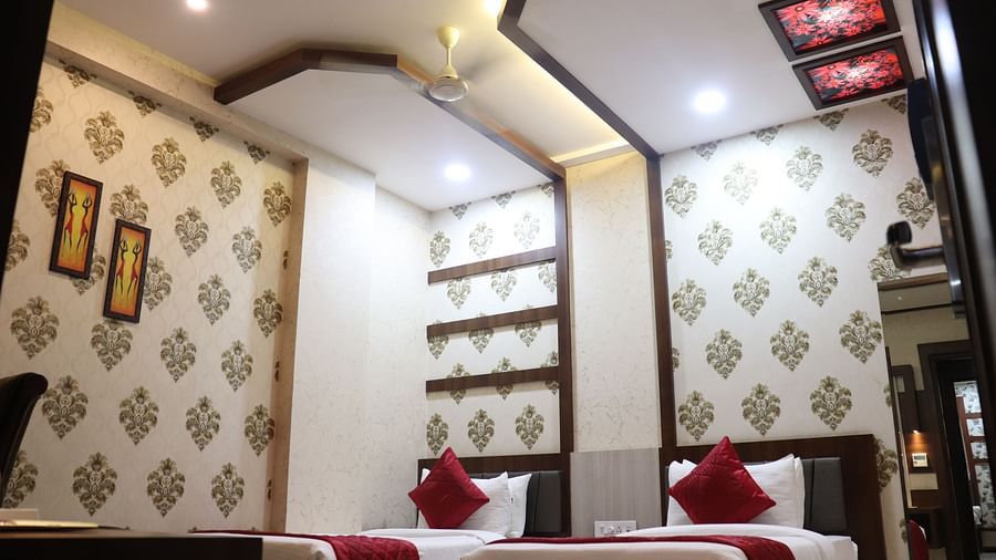 A spacious room with twin beds and patterned wallpaper at Hotel Uday Palace.