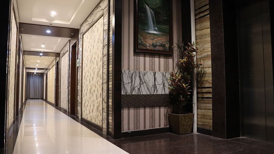 A well-lit corridor leading to the rooms at Hotel Uday Palace.