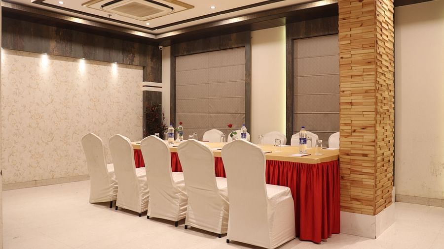 A large table with chairs on both sides, illuminated by bright lighting at Hotel Uday Palace.