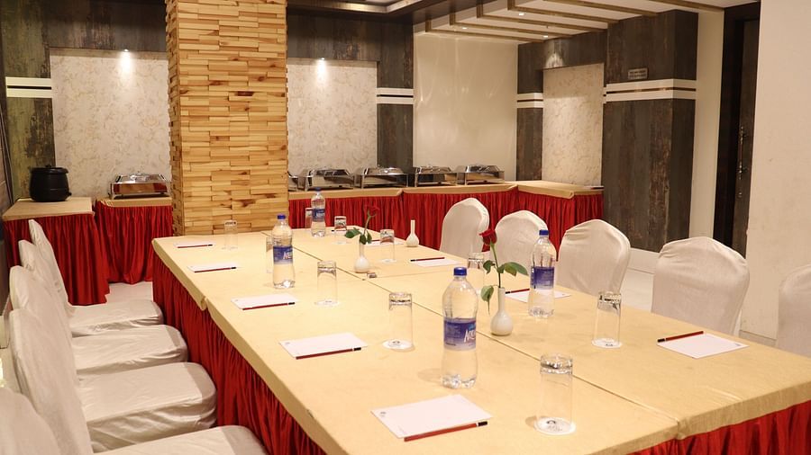 A close-up view of a large table with chairs on both sides, set with stationery and water bottles at Hotel Uday Palace.