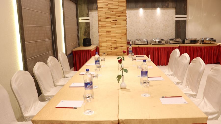 A contemporary meeting room with white chairs and wooden table setup at one of the best modern banquet halls in Varanasi - Hotel Uday Palace.
