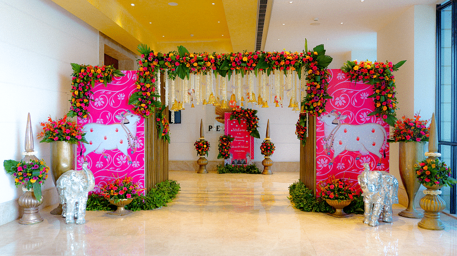 An indoor venue with a white floor and floral decorations, including pink and white flowers, suggesting a wedding ceremony or reception.