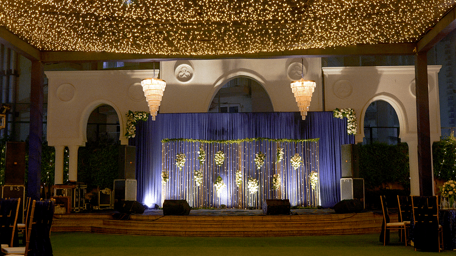 An outdoor venue at night, decorated for a wedding or event, with a covered stage and a building in the background.