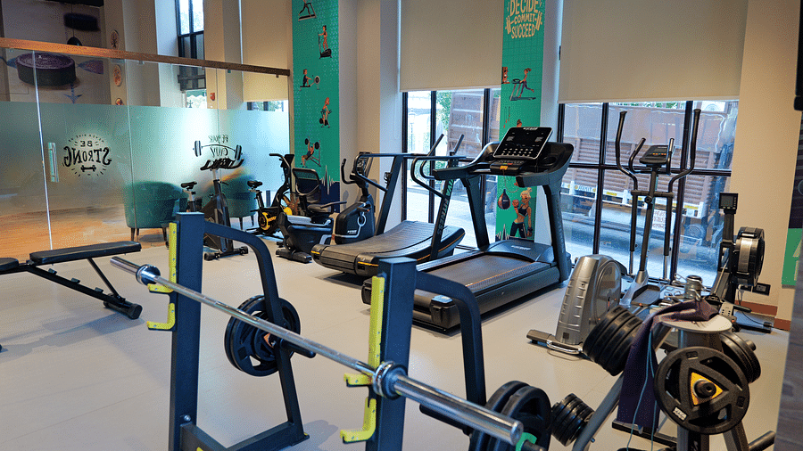 Interior of the gym at The Gaurs Sarovar Premiere, featuring various exercise machines and equipment.